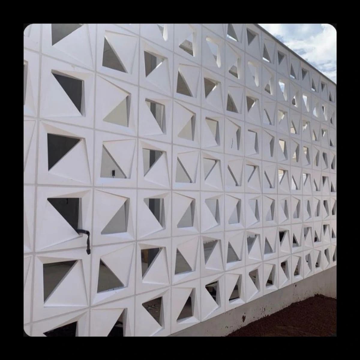 Muro construído com cobogós Citadino Dupla Face em concreto pré-moldado, módulos triangulares vazados em série formando ritmo geométrico contínuo, acabamento branco · Central do Concreto Ivoti RS