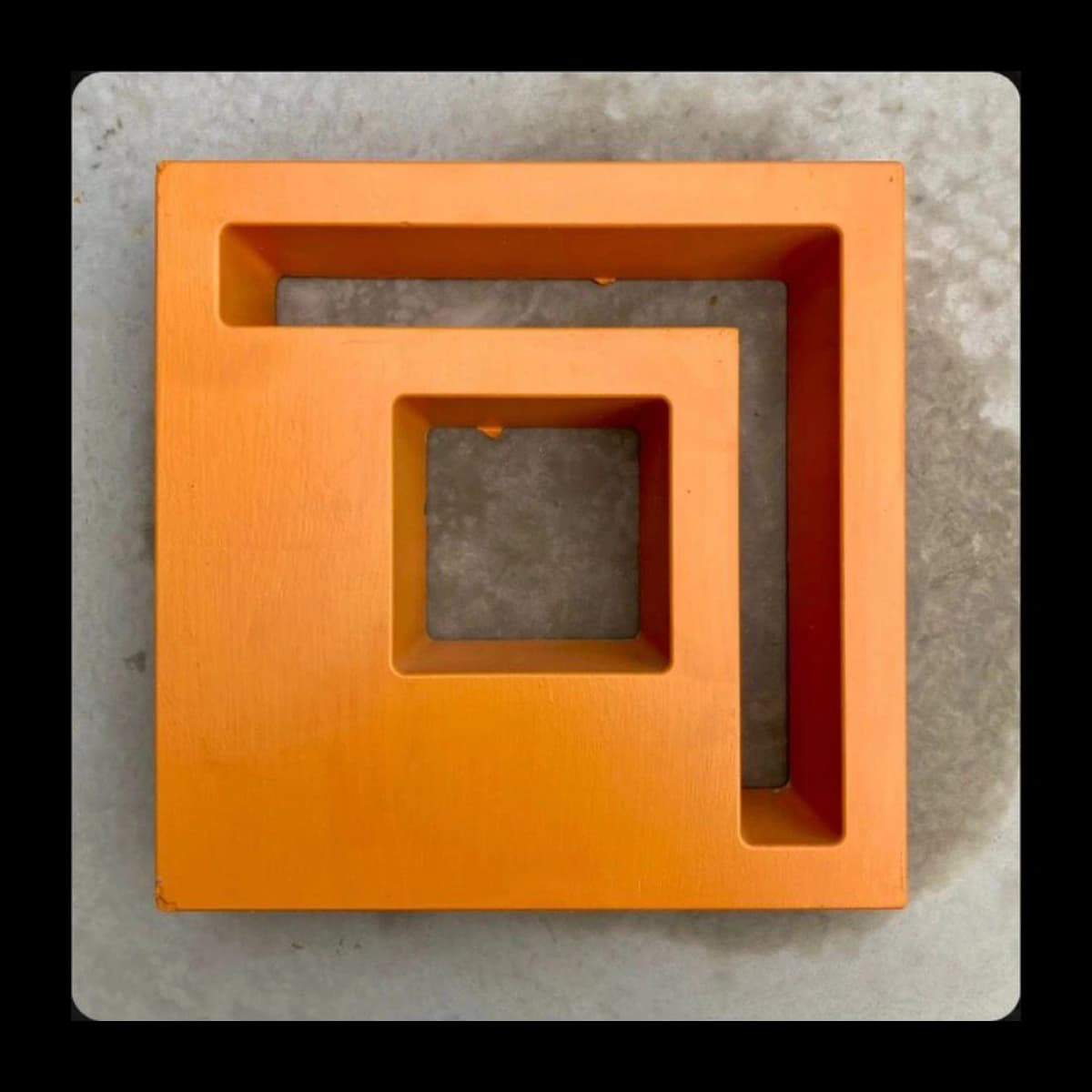 Cobogó modelo Poente em concreto pré-moldado · geometria em L espelhado formando espiral interna, acabamento laranja sobre base cinza · Central do Concreto Ivoti RS