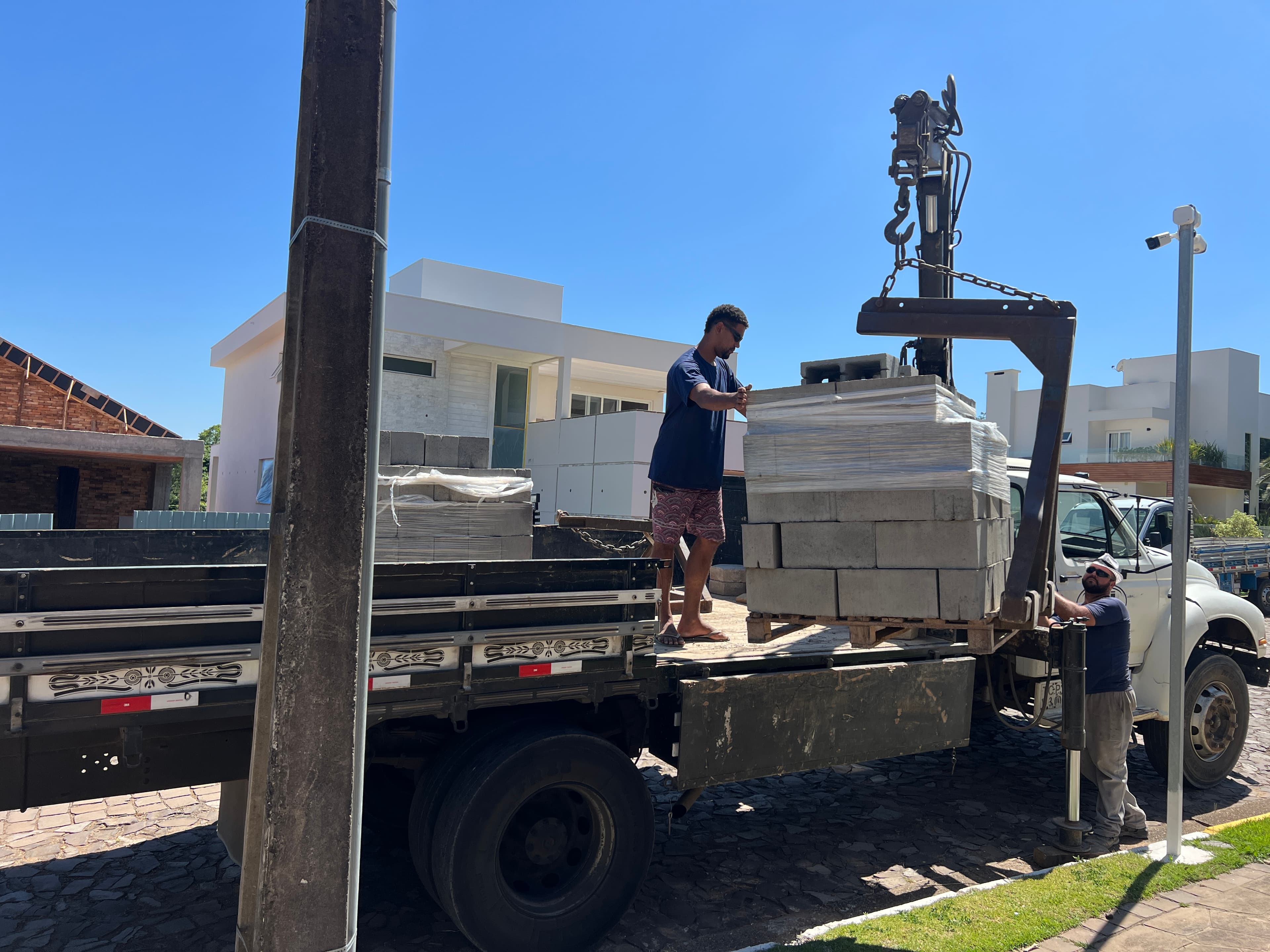 Caminhão Munck da Central do Concreto descarregando paletes de pré-moldados em obra residencial