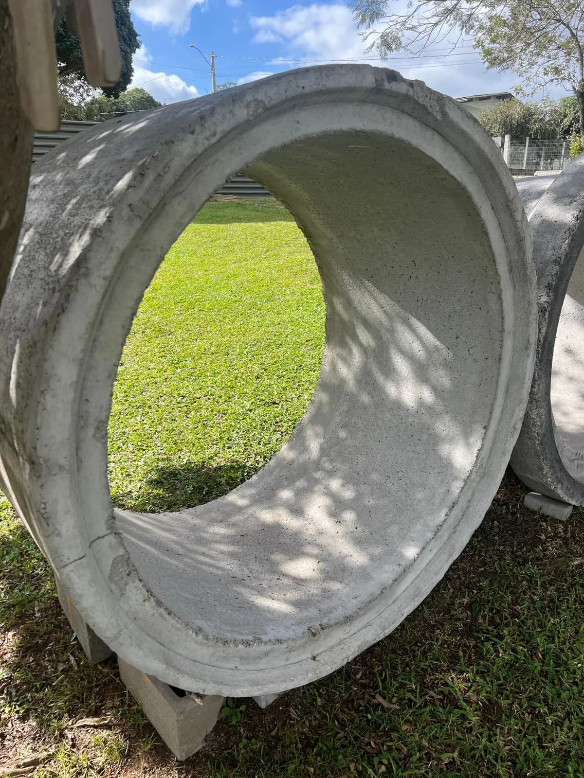 Tubo de concreto deitado na grama, visto de frente