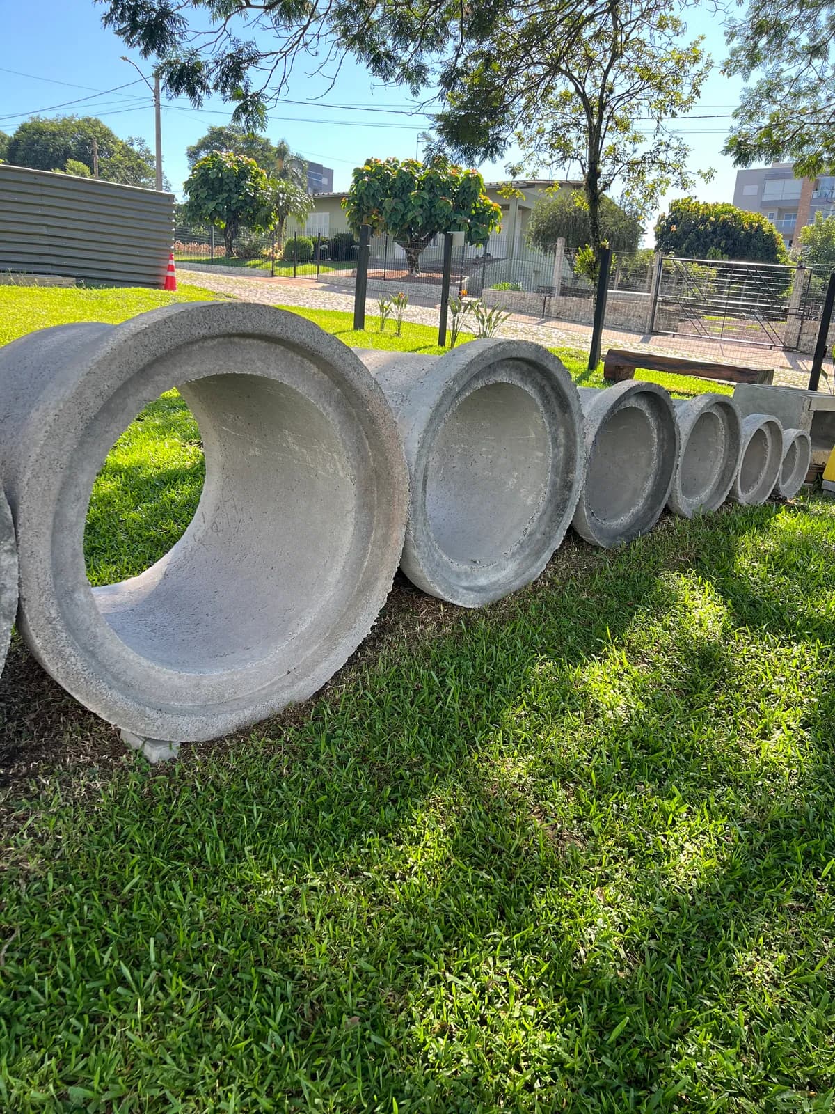 Fileira de tubos de concreto ponta e bolsa em ordem decrescente de diâmetro em bairro residencial · Central do Concreto · Ivoti RS